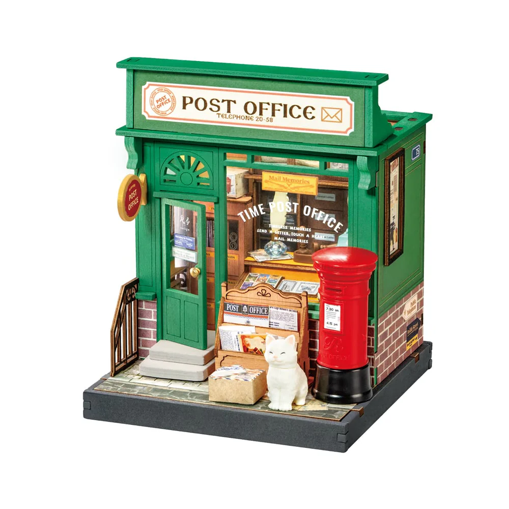 Green old fashioned post office with red letter box outside next to a white cat and magazine rack, inside has post office details
