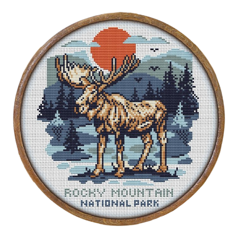 Finished view of rocky moutain national park cross stitch featuring a moose with setting sun front of blue moutains