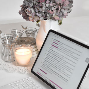 A laptop, flowers and lighted candle