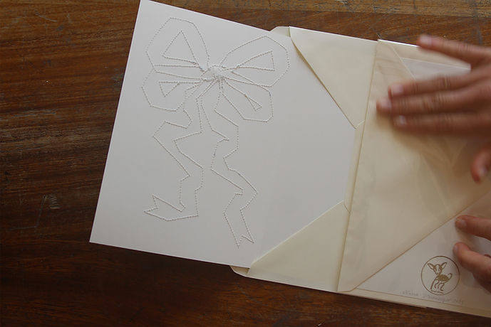 An anniversary card is being packed into an envelope. It is open, showing the hand stitching on its interior.