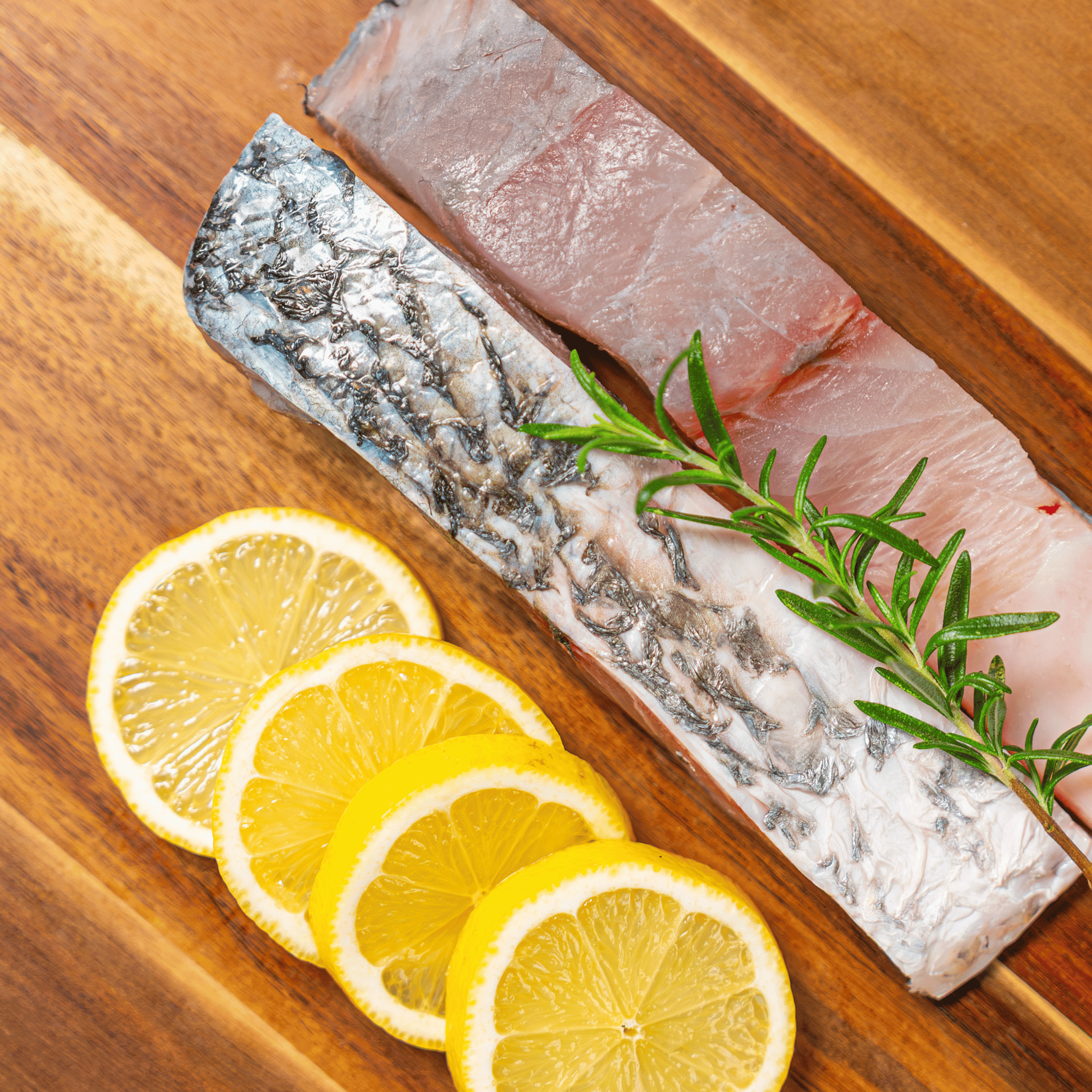 Fresh saltwater barramundi portions from Moofish, two skin-on fillets with firm white flesh, neatly cut and ready for cooking
