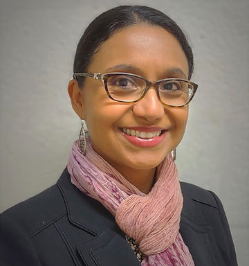 Florencia wearing a blazer, a pink scarf, and glasses.