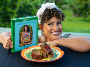Omi con su libro y el meatloaf relleno de mofongo servido en un plato. Receta de su libro Cooking Con Omi A Love Story to Puerto Rican Home Cooking.