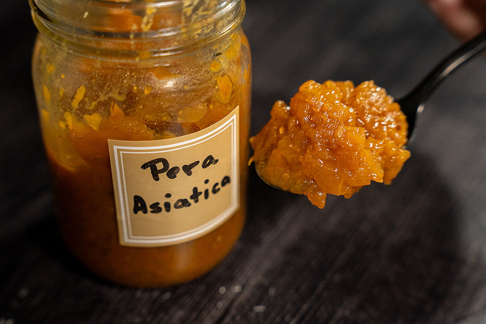 Una cuchara llena de jalea de pera al lado de su jarra