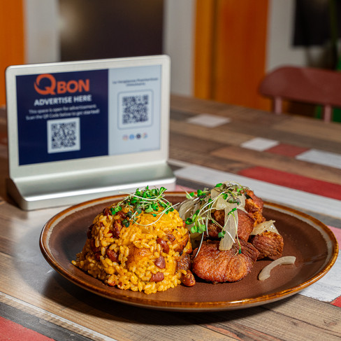un plato de arroz con habichuelas y carne frita. hay una pantalla de qbon en el fondo