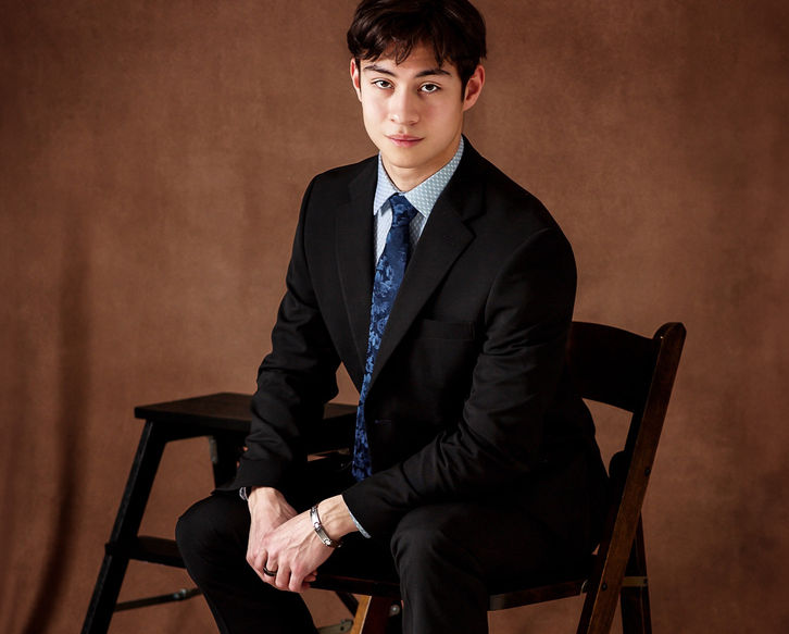  A young entrepreneur boy sitting in a black business suit with a blue tie and barefoot for branding ideas and head shot at the best pictures by Portrait by Taru studio photo session for a timeless and classic magazine style photoshoot in Minnetonka Minnesota MN Midwest.