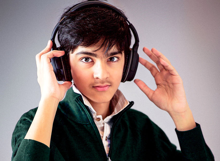 An Eden Prairie styling and Classy high school senior class of 2025 boy in a fashion formal style green boy sweater over a button up collared shirt and ear video gaming head phones posing in a studio photo shoot session for his senior pictures by Portrait by Taru, a Minneapolis MN based Maternity baby and family photographer in Edina Minnesota MN Midwest.