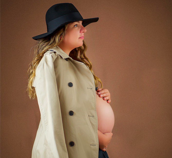 Maternity photo session of a 36 week pregnant woman with blonde hair hiding the pregger belly by a tan trench coat and black hat for a photo shoot by twin cities baby child and family photographer Taru Chhaya of portraitbytaru in Minneapolis Minnesota Midwest