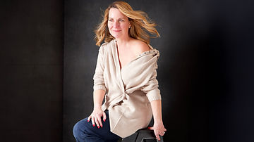 A woman c suite executive working for a major leading corporate bank is wearing a blue jeans and an off white off shoulder sweater featuring in journeys of women series , showing strength , wisdom and grace of every lady at Portrait by Taru studio photoshoot, a women and family photographer in Plymouth, Minnesota, Midwest MN