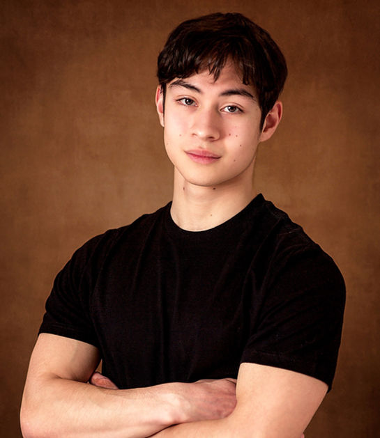 A cute branding Studio session for a very handsome Orono MN High School Senior guy where he is wearing a simple black boys tee and blue denim jeans with his strong body build arms crossed and is making the best authentic but kind eye contact with the audience for a photoshoot session by Portrait by Taru, a childhood and family photographer in Minnetonka Minneapolis Minnesota MN Midwest.