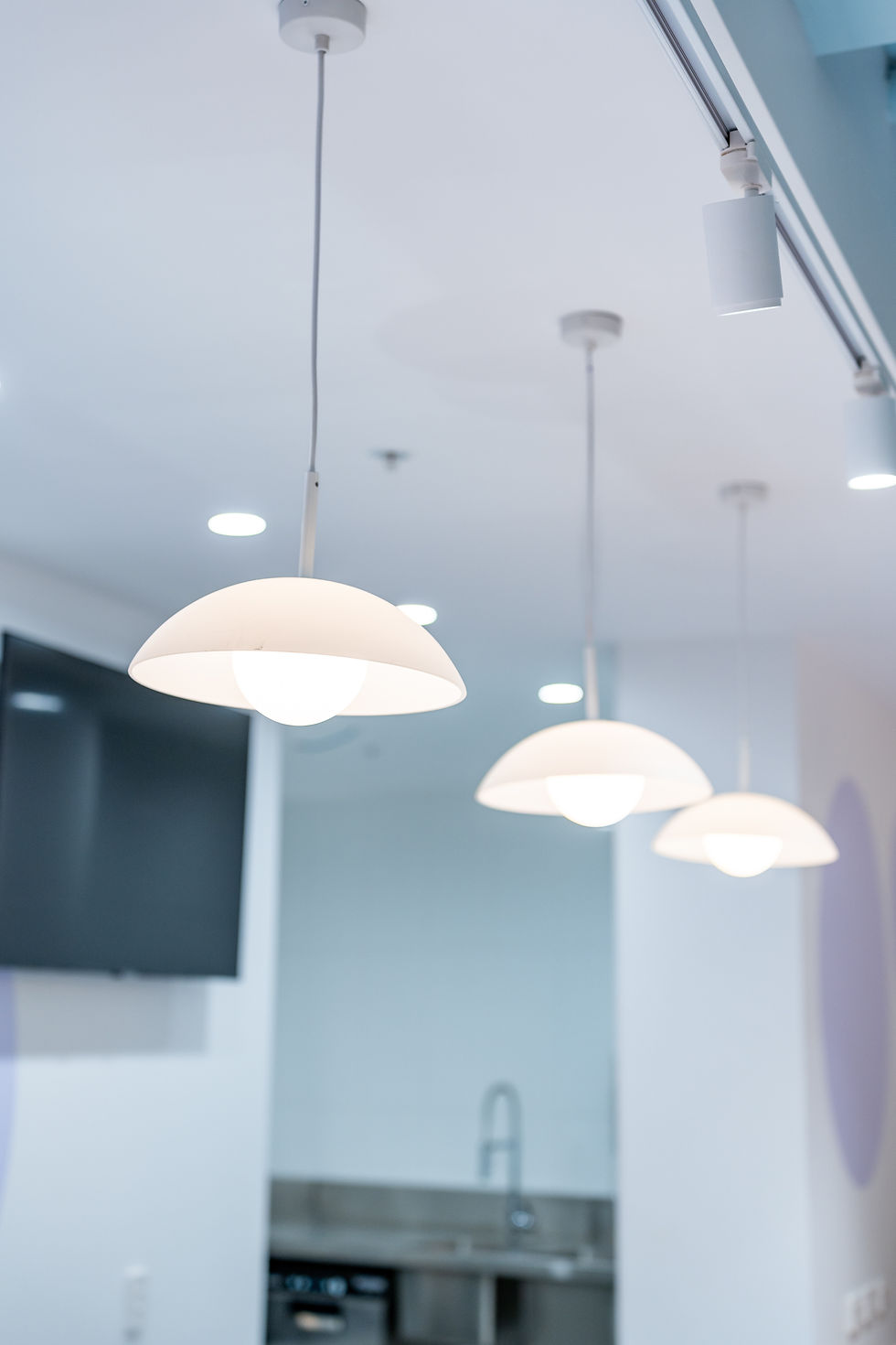 Three modern white dome pendant lights hanging in a row.