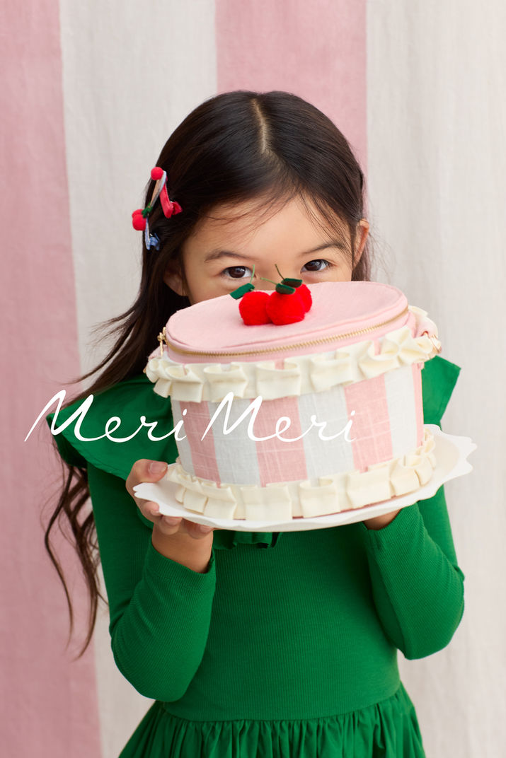 Mädchen in grünem Kleid mit einer rosa Geburtstagstorte