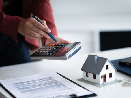 Person kalkuliert die Kosten einer Immobilie, Taschenrechner in der Hand