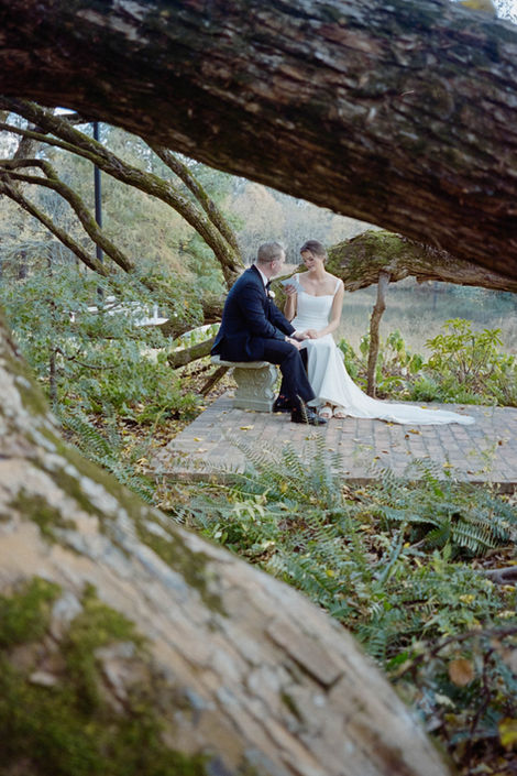 Bride and groom sitting together after firstlook outdoors framed by tree branches in a natural setting during wedding
