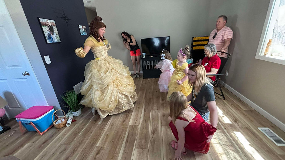 Princess Belle entertains children dressed as princesses in a living room. Adults watch, one photographs the scene.