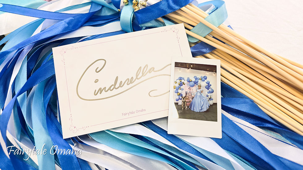 A card signed "Cinderella" lays on top of blue ribbon wands with a polaroid photo of a princess.