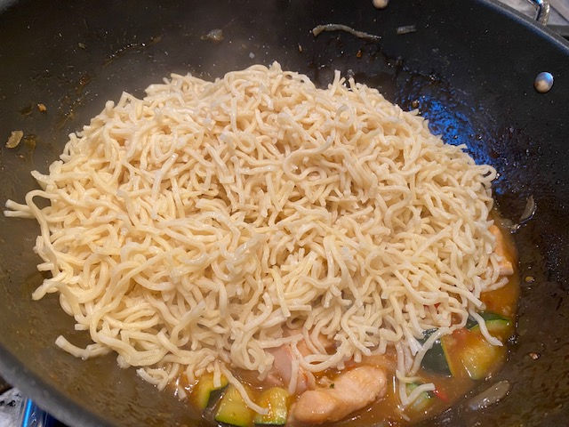 Add strained noodles to wok