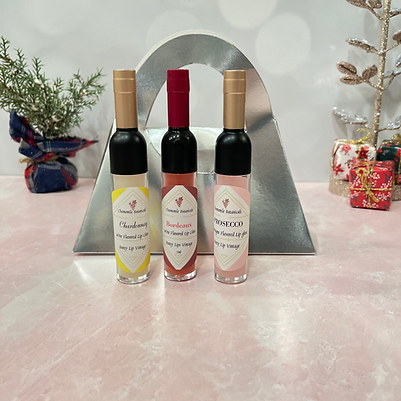 Three wine and champagne infused lip glosses from Chamomile Botanicals Boozy Lip Care collection in wine bottle applicator bottles