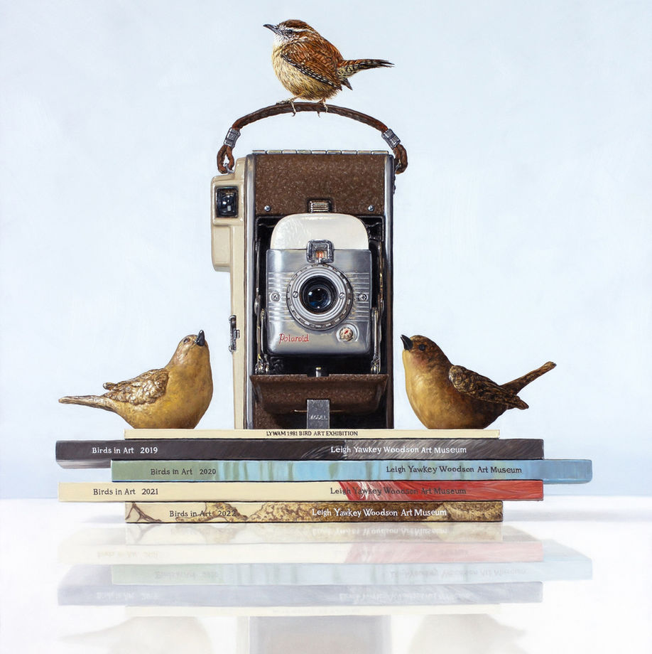 Wren in Art, by Rebecca Korth, is a hyper-realistic painting of a wren perched atop a vintage camera. The camera is flanked by wren sculptures. All of this is sitting on top of a stack of Birds in Art exhibition catalogs.