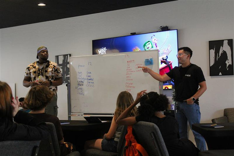 Two men presenting ideas on a whiteboard to an attentive audience.