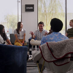 Five young people collaborating in a bright office, 'create' sign.