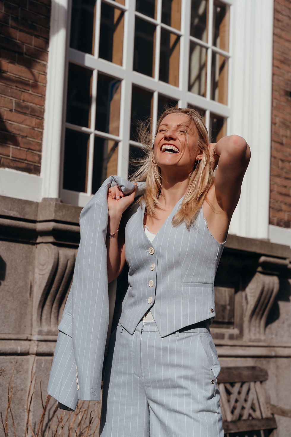 Woman in dark t-shirt and cap pointing upward while standing on desert rocks under blue sky