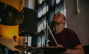 man in red crew neck shirt playing drum_