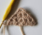 brown crochet triangle with a yellow crochet hook on a white background.