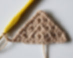 brown crochet triangle with a yellow hook on a white background
