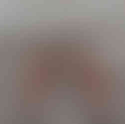 Pink and brown crochet rabbit ears with a metal crochet hook on a brown wooden background.