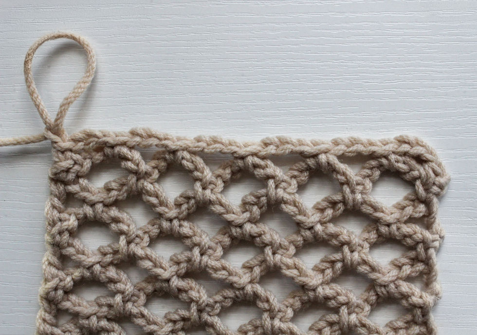 Beige crochet diamond mesh on a white wooden background, featuring intricate loops and knots, creating a lattice design.