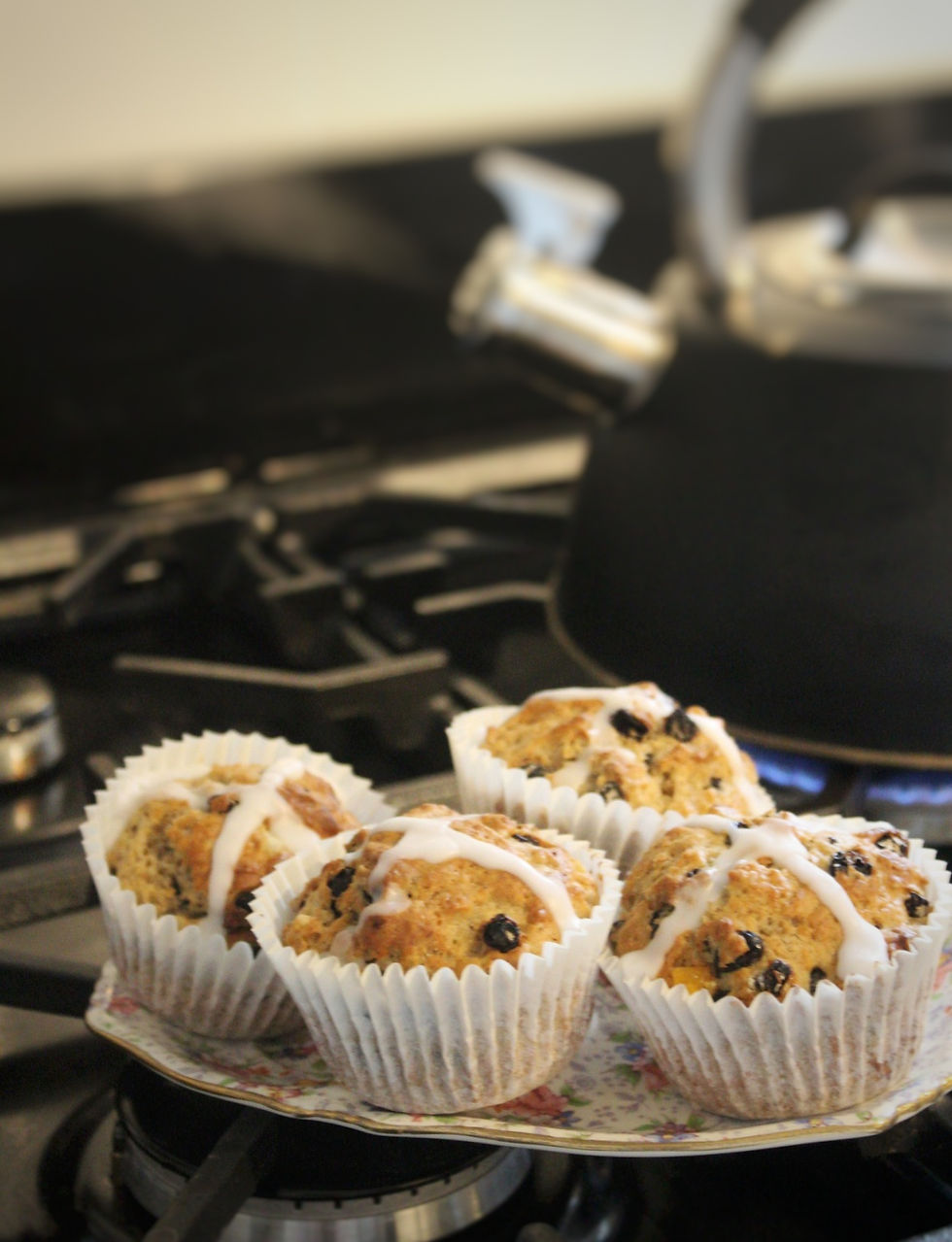 Hot cross muffins on plate by boiling whistling kettle