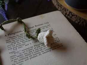A crochet flower bookmark lying on an open book. Dark wooden background.