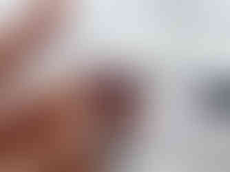 Close-up of a hand crocheting with a hook, using purple yarn wrapped around fingers against a marbled background.