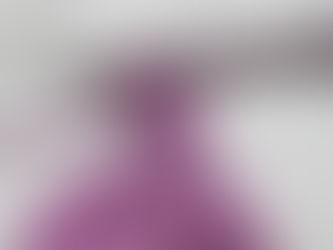 A silver crochet hook loops purple yarn into a pattern against a white background.