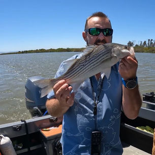 Anglers trolling the Napa River for striped bass alongside new fishing gear, custom spider weights, a limited-edition Daiwa reel, vintage Orvis tackle, and Pond Stars fishing collections displayed at Sweeney's Sports.