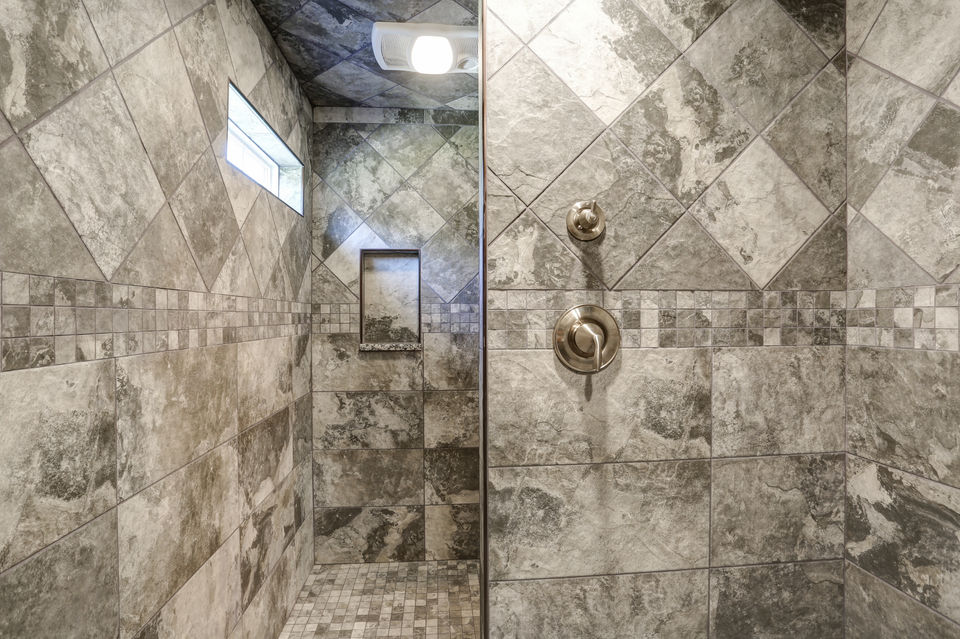walk-in tile shower with transom window, niche, and corner shelving