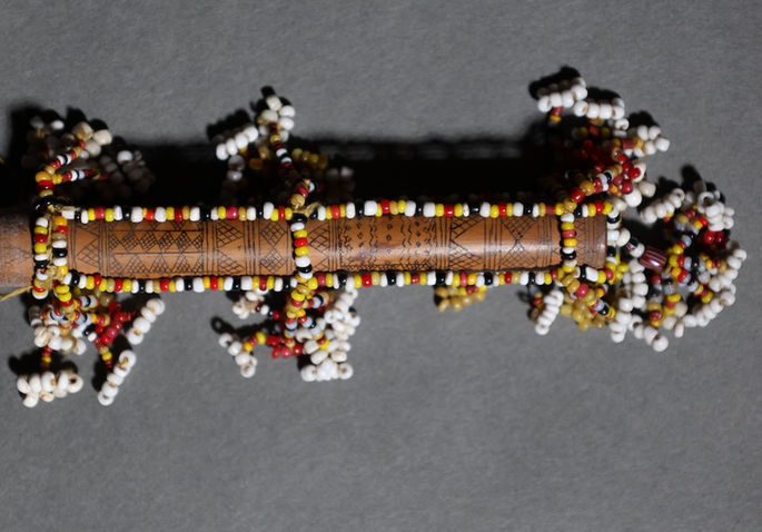 The body of the container is adorned with intricate etchings of traditional designs and beadwork