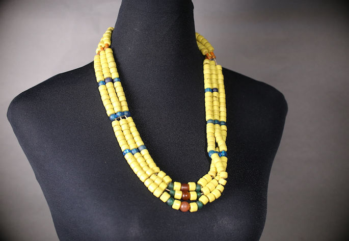 A display shot of a three-layered necklace featuring dominant yellow beads, accented with blue, aquamarine, and red translucent beads
