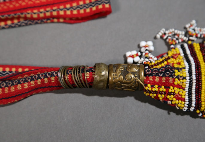 A close-up shot focusing on the ring-like brass material attached to the belt’s ends with elaborate relief designs.