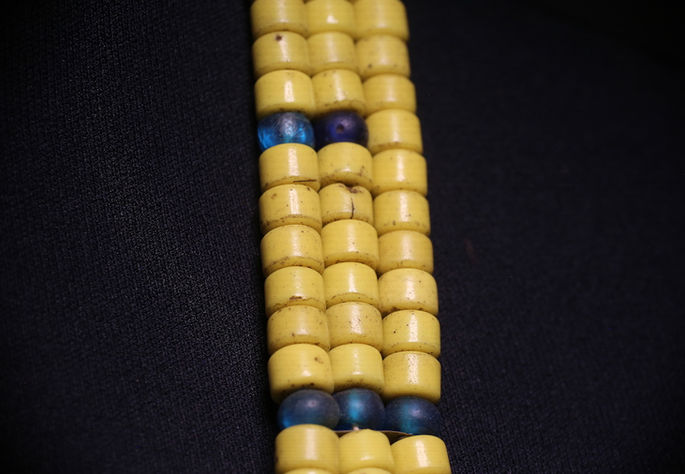 Dark blue beads act as separators between the yellow beads, which emphasizes the layering of the necklace