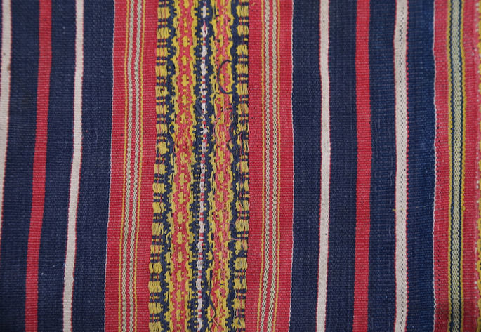 Brocade linear and geometric designs, embedded in the thicker stripes of the skirt, are shown in detail