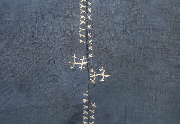 A close-up shot featuring two lizard-like motifs, alongside rice plant patterns, which outline the textile panels stitched together by the staccato pattern, locally known as the inar-arabas or the caterpillar-like pattern