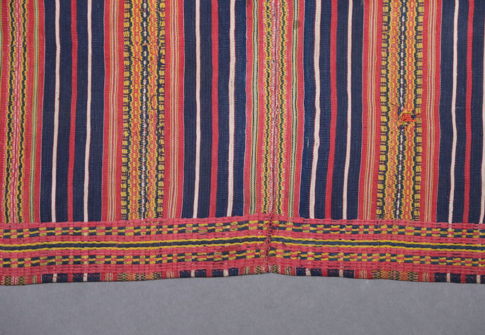 The skirt has side borders that feature woven brocade checkered designs in indigo, red, and yellow
