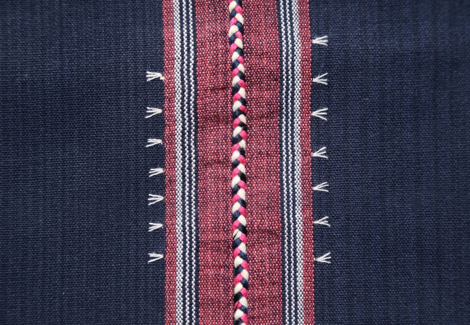 A close-up shot of the white embroideries, showing details on the rice stalks embroidery and braided threads