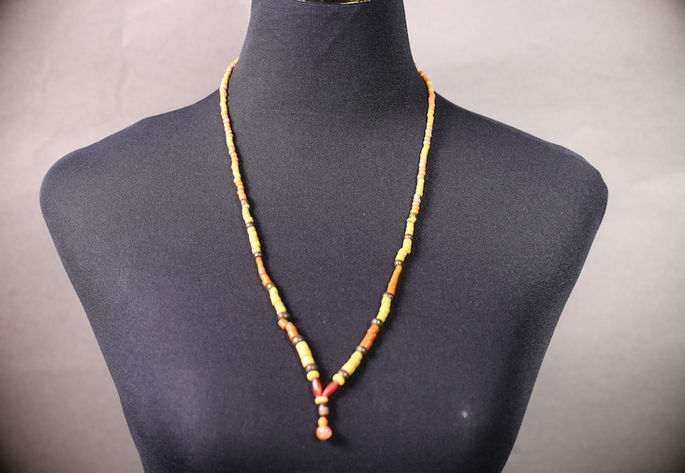 A display shot of a single-strand, chest-length bead necklace with hexagonal carnelian beads and a banded agate centerpiece