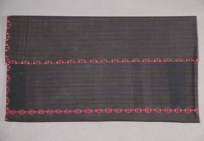 A hero shot of a three-paneled striped gray and violet skirt with red embroideries on its joineries and borders