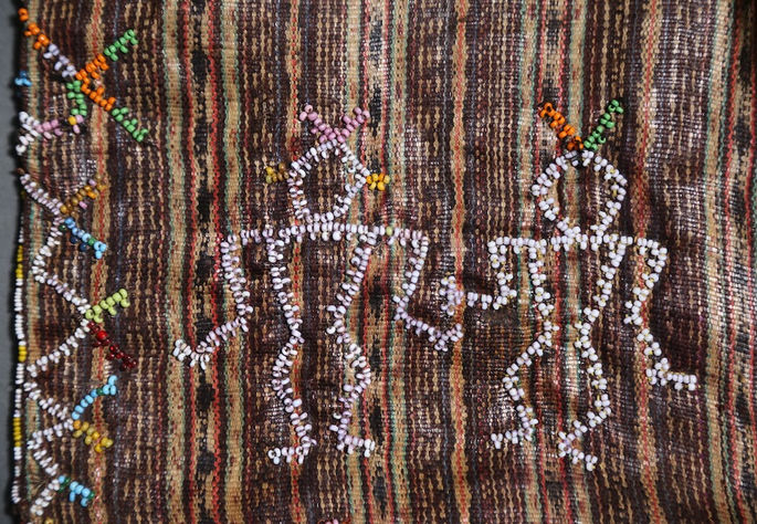 A detailed shot highlighting two anthropomorphic figures rendered in beadwork