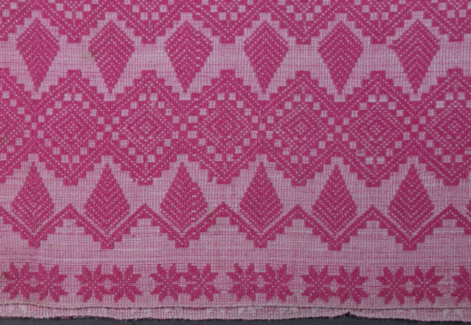 A closer look at the blanket featuring the patterns of diamond-like motifs creating the design. Near the blanket’s edges are flower-like motifs.
