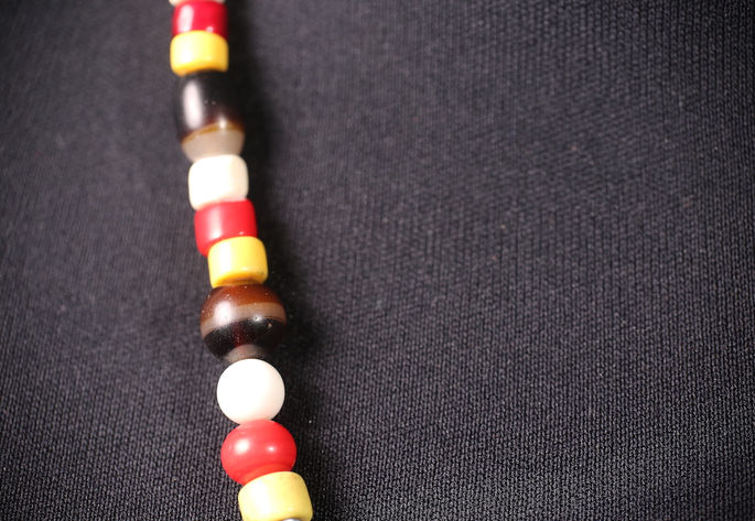 A detailed shot capturing a kamuntara bead, followed by a white bead and an opaque striped glass bead known as pinispisao